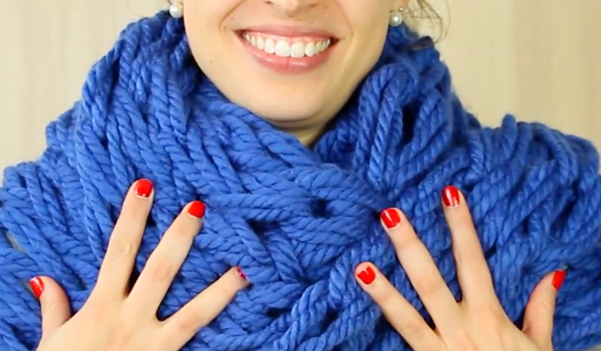 Eine junge lächelnde Frau trägt einen blauen Loopschal.