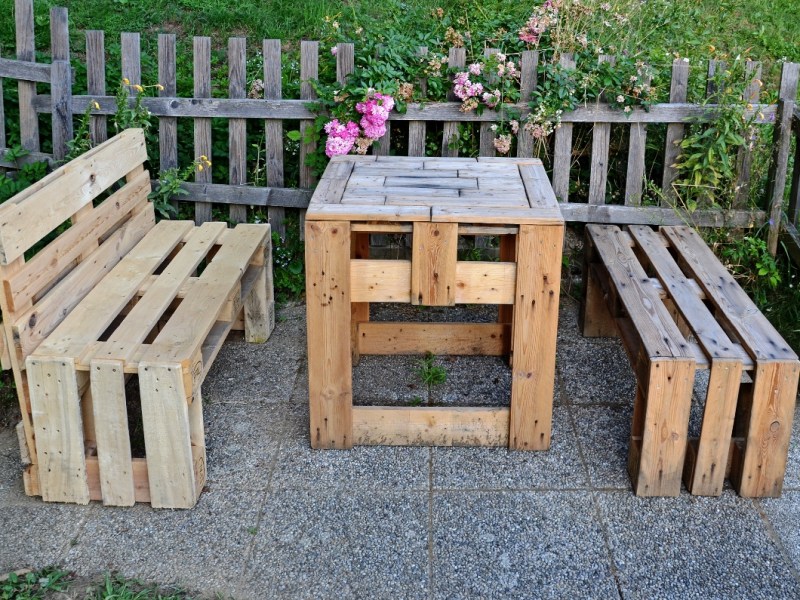 Ein Tisch und zwei Bänke in einem Garten, aus Euro-Paletten gebastelt.