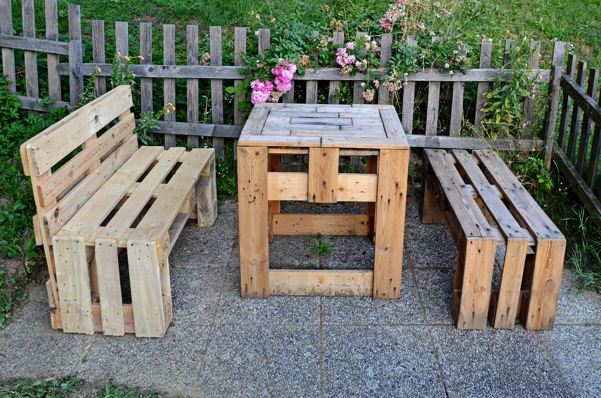 Ein Tisch und zwei Bänke in einem Garten, aus Euro-Paletten gebastelt.