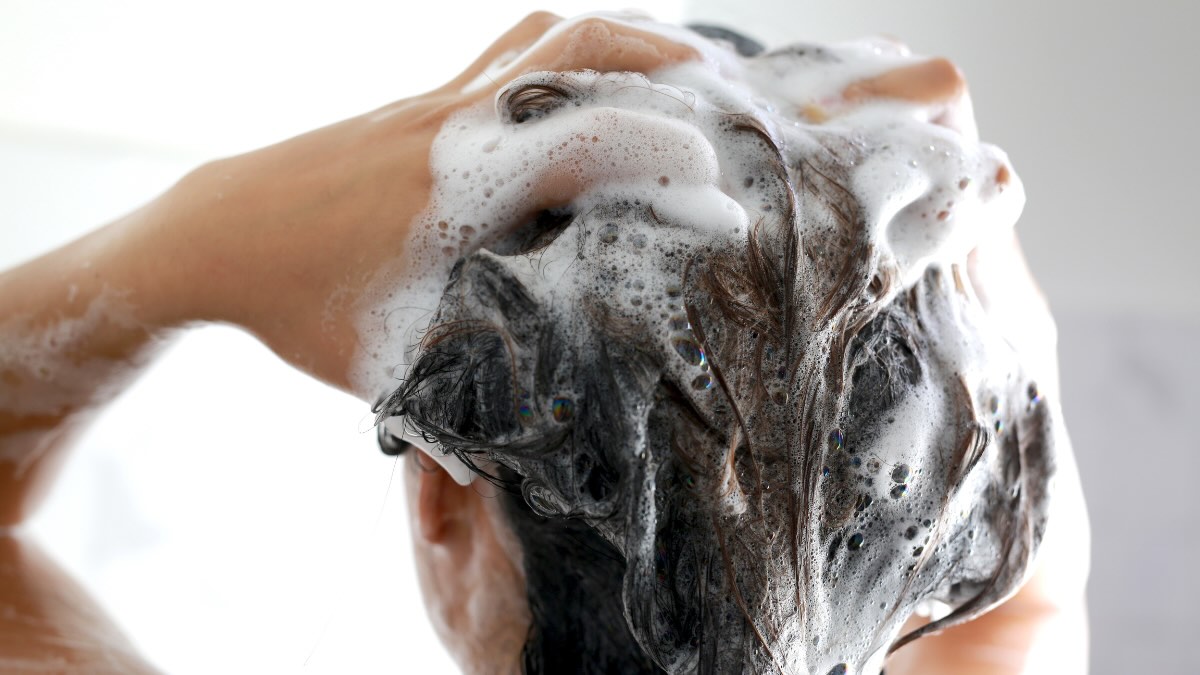 Eine Person schÃ¤umt seine Haare mit Shampoo ein.