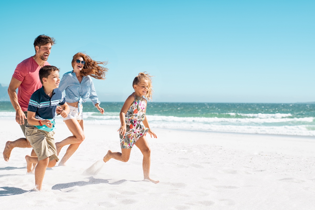 Eine glückliche Familie läuft über einen Strand im Sommer.