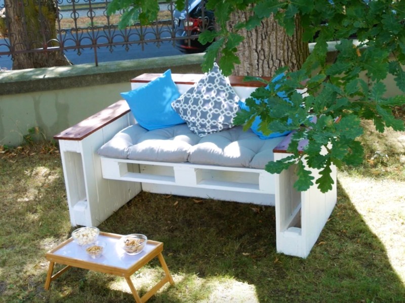 Ein DIY-Sofa aus Paletten steht in einem Garten.