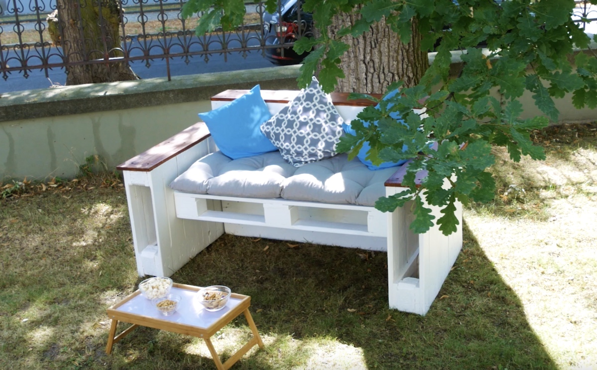 Ein DIY-Sofa aus Paletten steht in einem Garten.