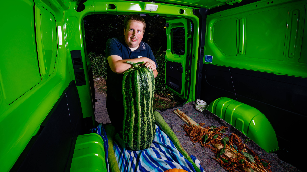 Ein Mann steht in seinem Laster und zeigt seine riesige Wassermelone.