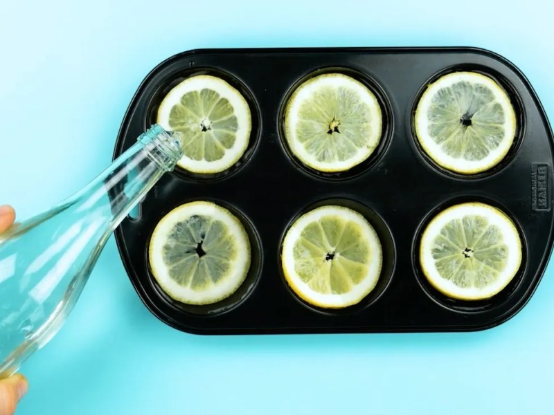 Zitronenscheiben in einer Muffinform werden mit Wasser begossen.