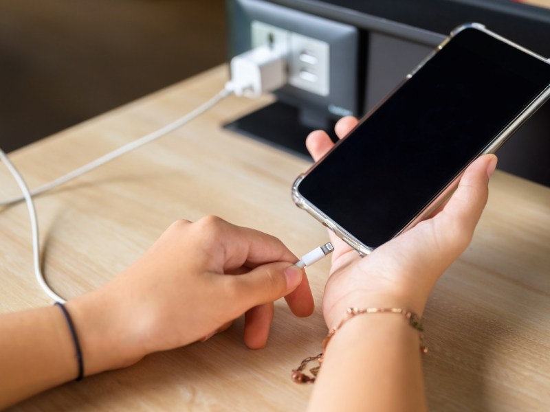 Eine Nahaufnahme eines Handys bzw. Smartphones, das an einer Steckdose geladen wird.