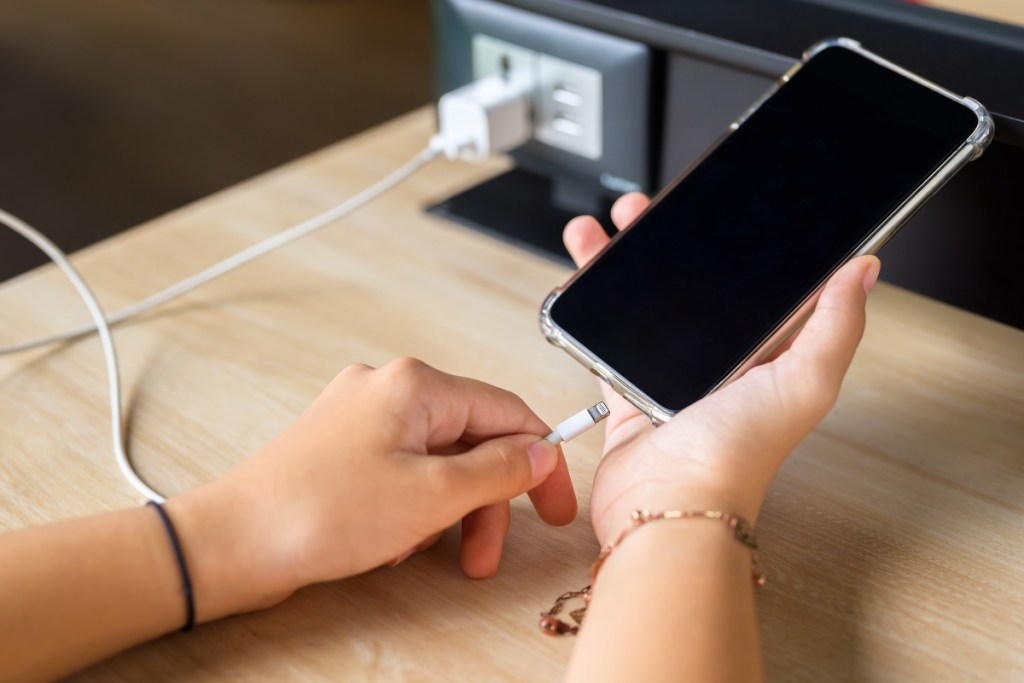 Eine Nahaufnahme eines Handys bzw. Smartphones, das an einer Steckdose geladen wird.