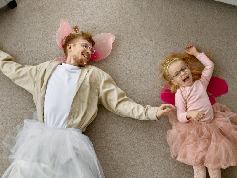 Vater und Tochter liegen in lustiger Verkleidung auf dem Boden