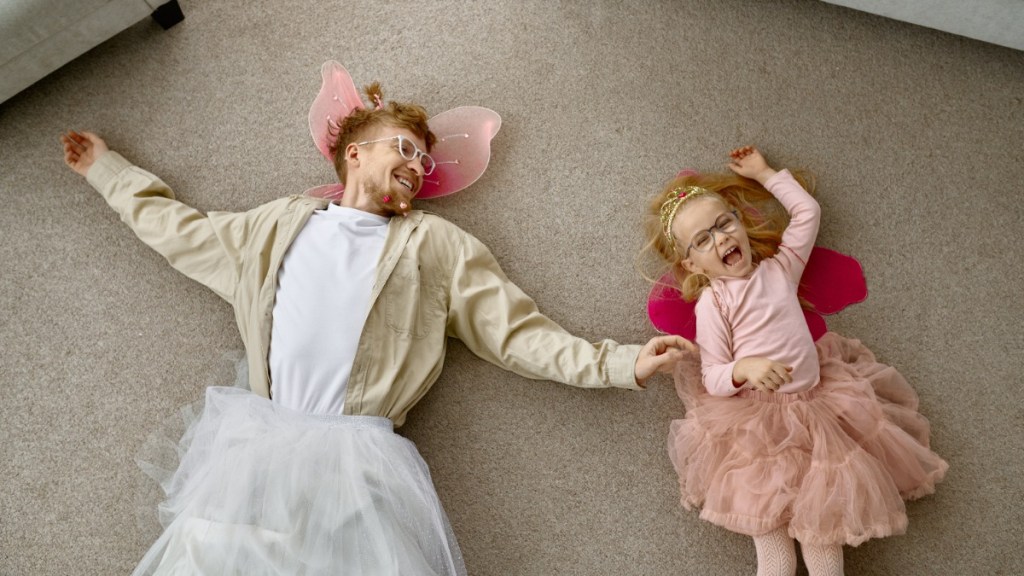 Vater und Tochter liegen in lustiger Verkleidung auf dem Boden
