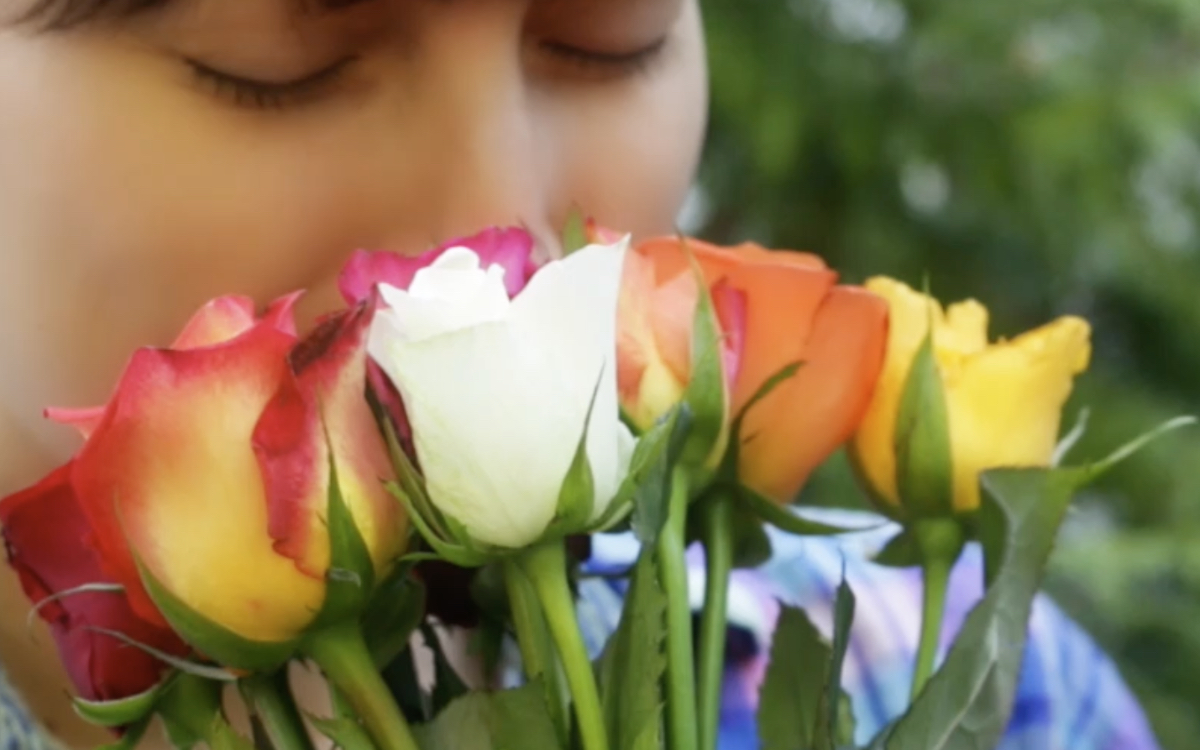 Eine junge Frau riecht an einem Strauß Rosen.