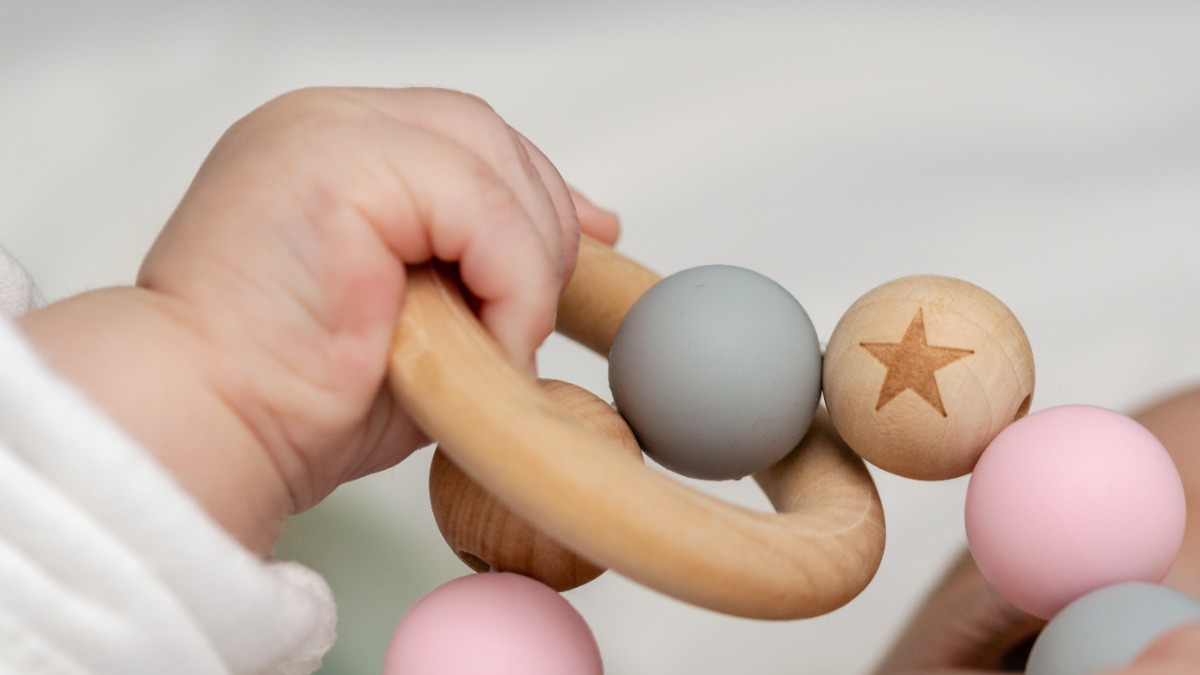 unnötige Produkte für Kinder: eine Babyhand greift nach einem Holzring