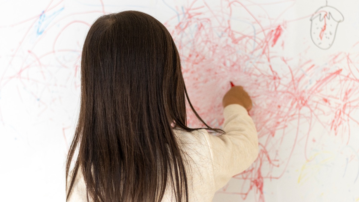 Mädchen malt mit einem roten Stift die Wand an