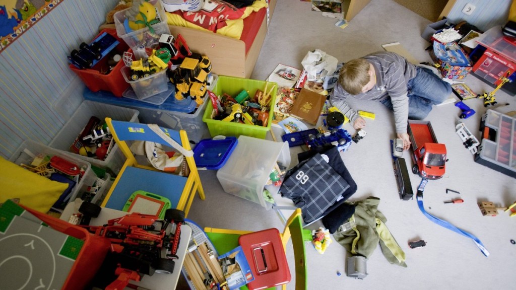Ein Junge spielt in seinem Zimmer inmitten von Spielzeug