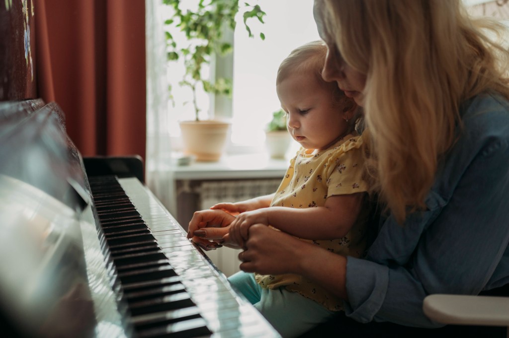 Mutter zeigt ihrem Kleinkind, wie man Klavier spielt