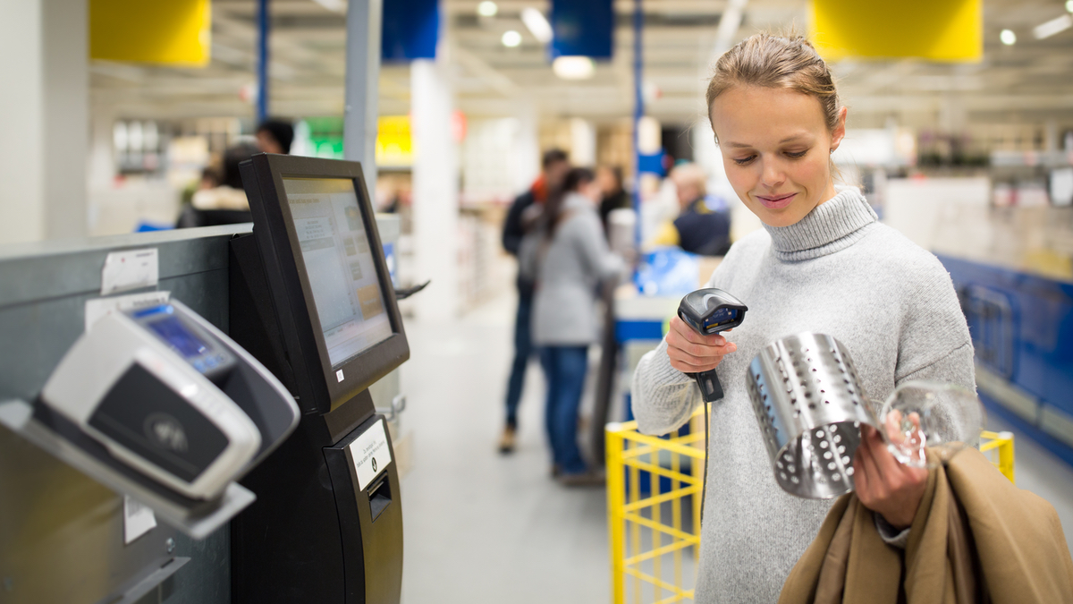 Eine Frau scannt einen IKEA-Besteckhalter an einer Self-check-out-Kasse.