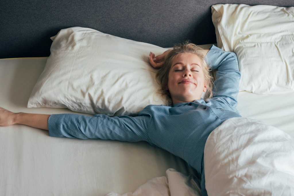 Eine Frau streckt sich in ihrem Bett aus.