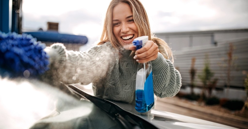 Frau putzt Autoscheibe.