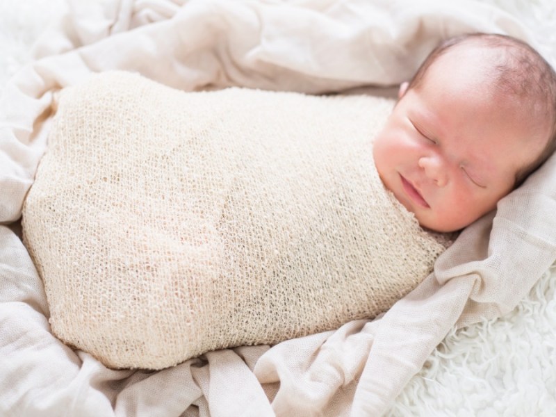 Ein Neugeborenes ist eingepuckt und schlummert friedlich