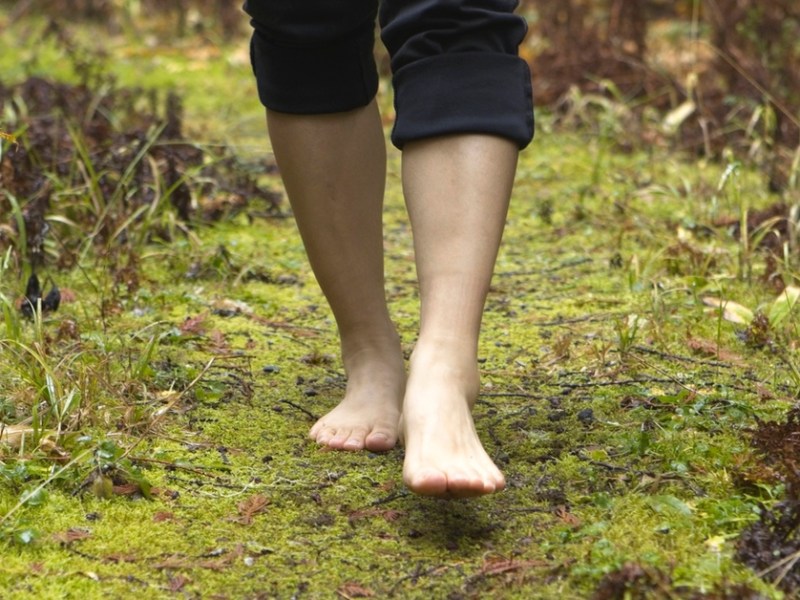 Jemand läuft barfuß durch den Wald.