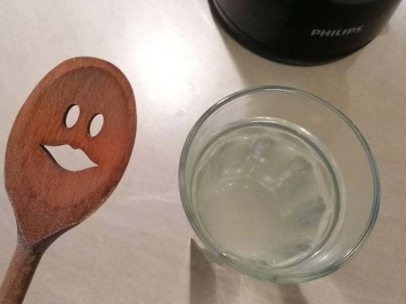 ein Holzkochlöffel neben einem Glas mit Wasser