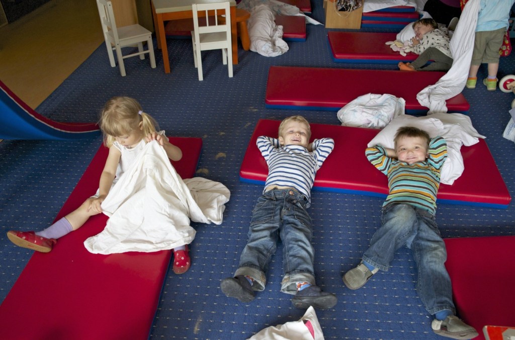 Kinder einer Kindertagesstätte legen sich im Ruheraum zum Mittagsschlaf hin.