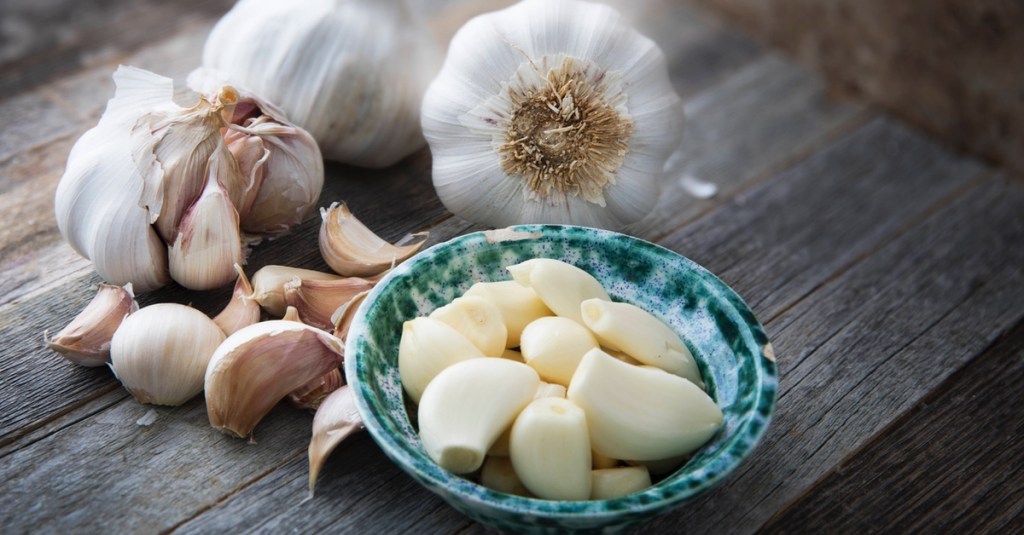 Knoblauchzehen liegen geschält in einer kleinen Schüssel.