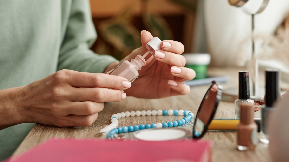 Eine Frau lackiert ihre FingernÃ¤gel mit hellem Nagellack.