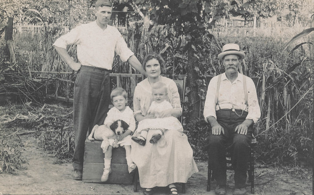 Family posing with a puppy in a garden