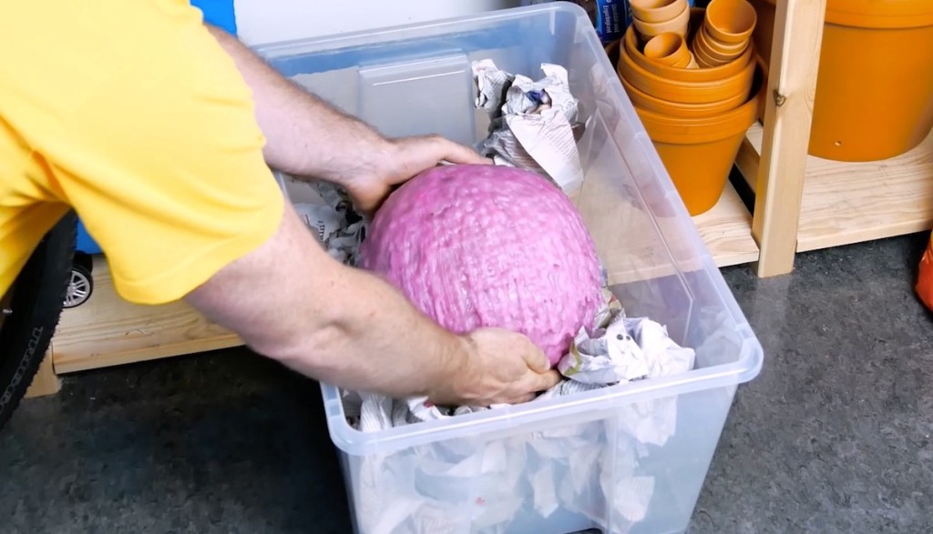 Eine mit Wachs betropfte Wassermelone wird in eine Plastikbox gepackt.