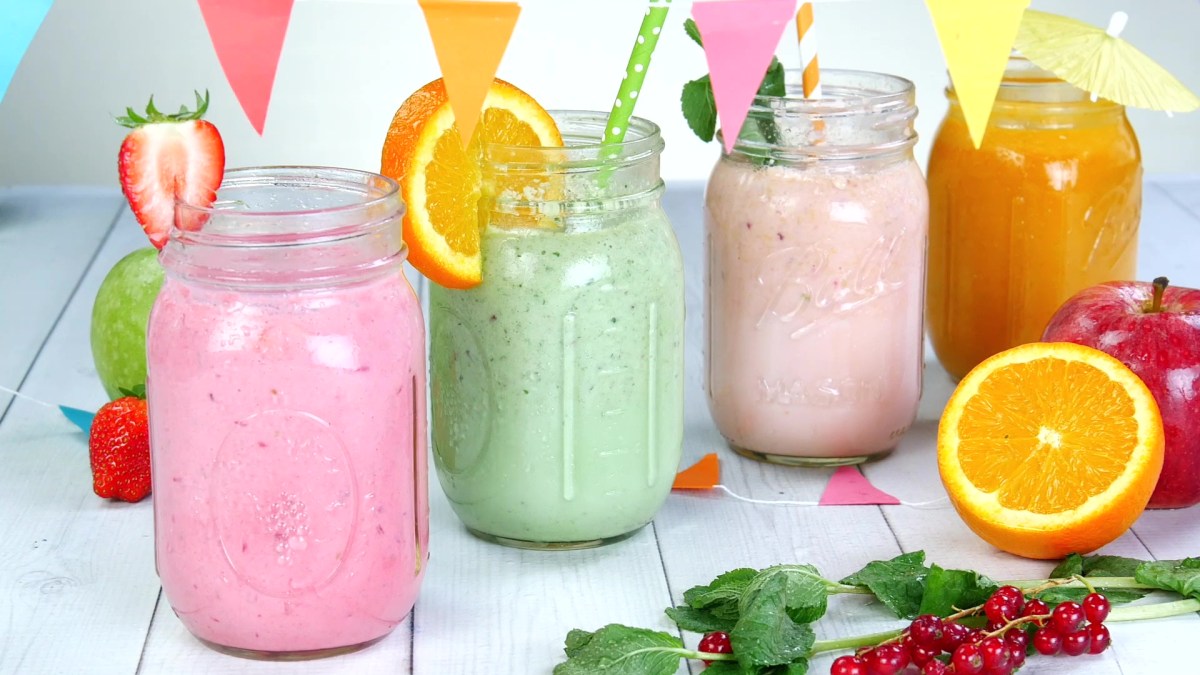 Vier fruchtige Smoothies in verschiedenen Farben in Smoothiegläsern angerichtet.