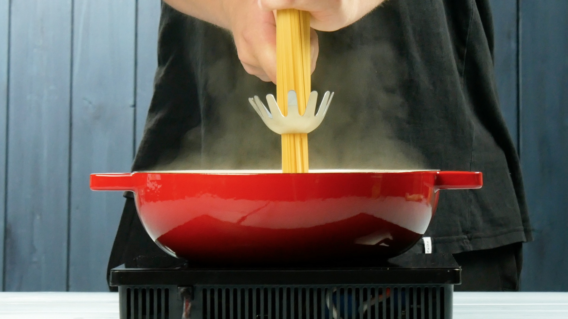 Eine Portion Spaghetti wird mithilfe eines Spaghetiilöffels abgemessen.