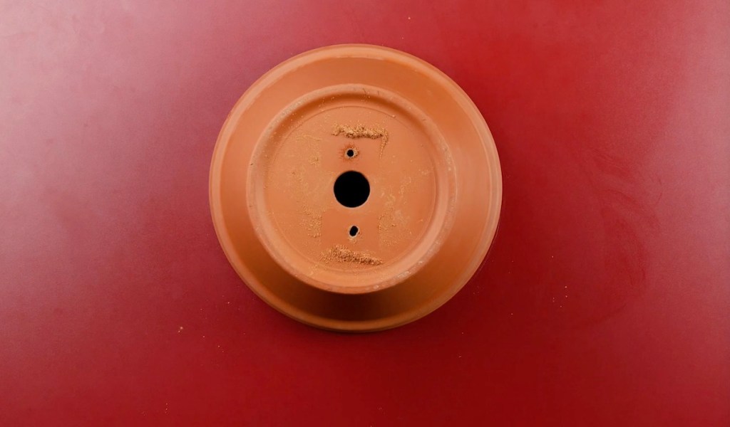 In einen Keramiktopf wurden zwei kleine Löcher in den Boden gebohrt.