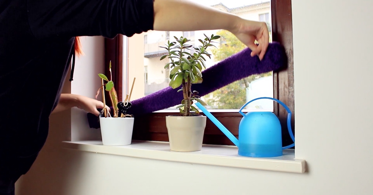 Ein zusammengerolltes Handtuch wird als Zugluftstopper vor ein Fenster gelegt.