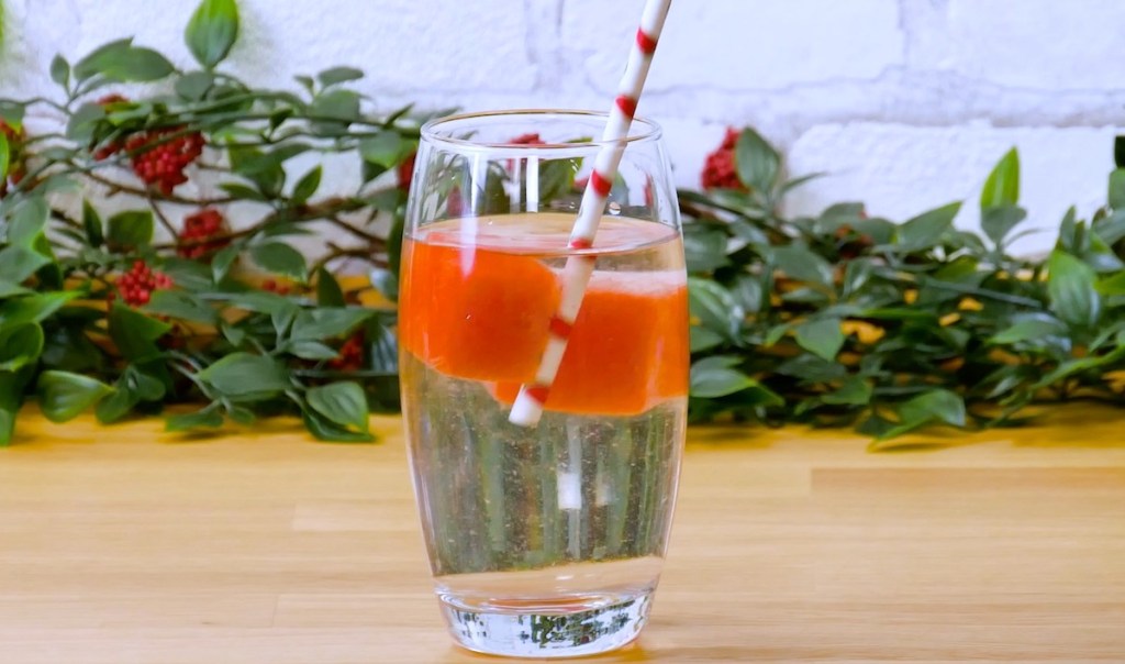 Ein Wasserglas mit Meloneneiswürfeln.