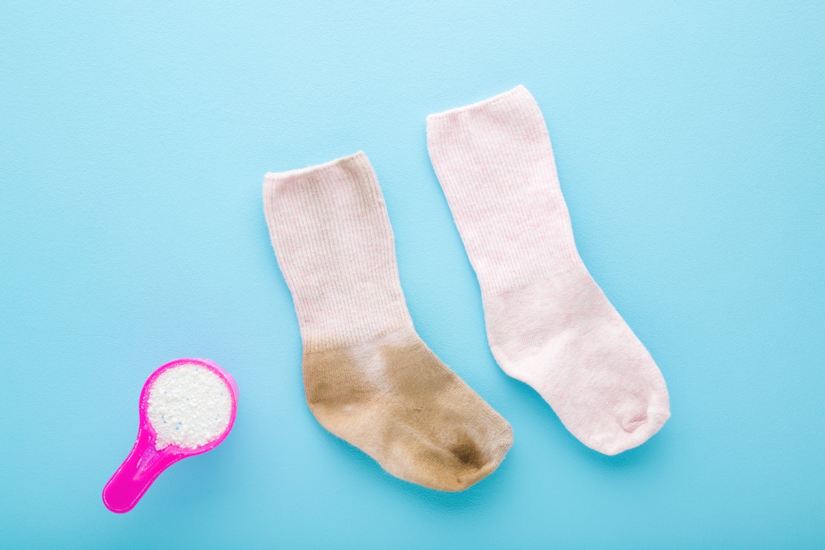 Ein Vorher-nachher-Bild von einer weißen Socke vor und nach dem Waschen vor blauem Hintergrund.
