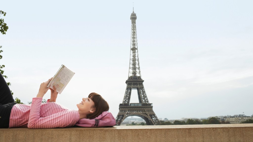 Frau liest ein Buch in Paris – im Hintergrund der Eiffelturm.