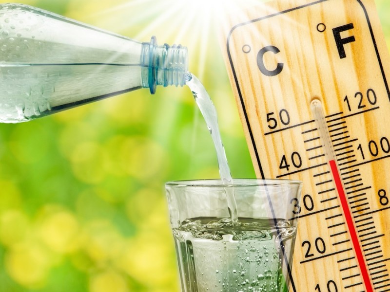 Wasser wird in ein Glas eingeschenkt, daneben ein Thermometer.