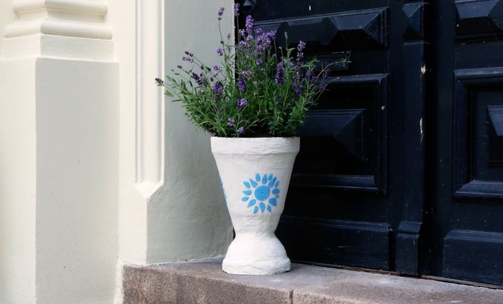 Ein weißer Pflanzenkübel aus alten Obertöpfen, mit Lavendel bepflanzt.