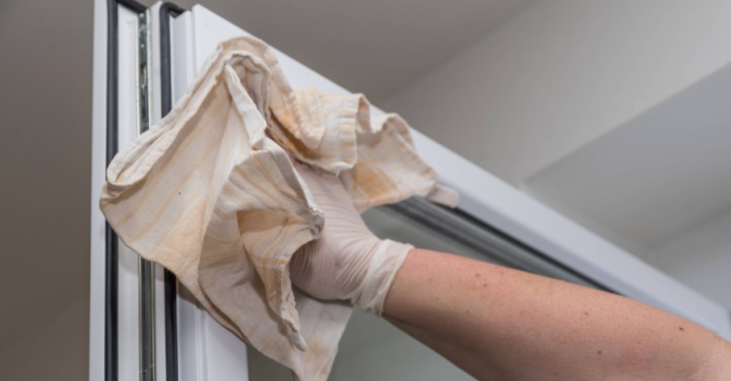 jemand putzt mit einem Putzlappen aus Leinen ein Fenster