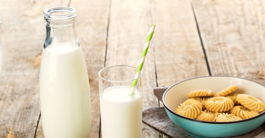 Eine Schale mit Keksen, eine Flasche mit Milch und ein Glas Milch mit einem Papierstrohhalm