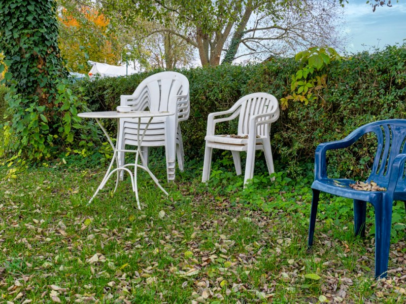 GartenmÃ¶bel und GartenstÃ¼hle stehen gestapelt in einem Garten.