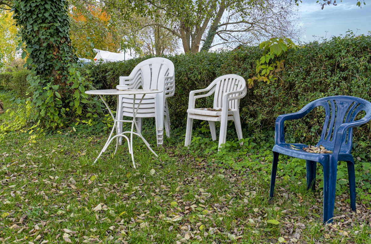 GartenmÃ¶bel und GartenstÃ¼hle stehen gestapelt in einem Garten.