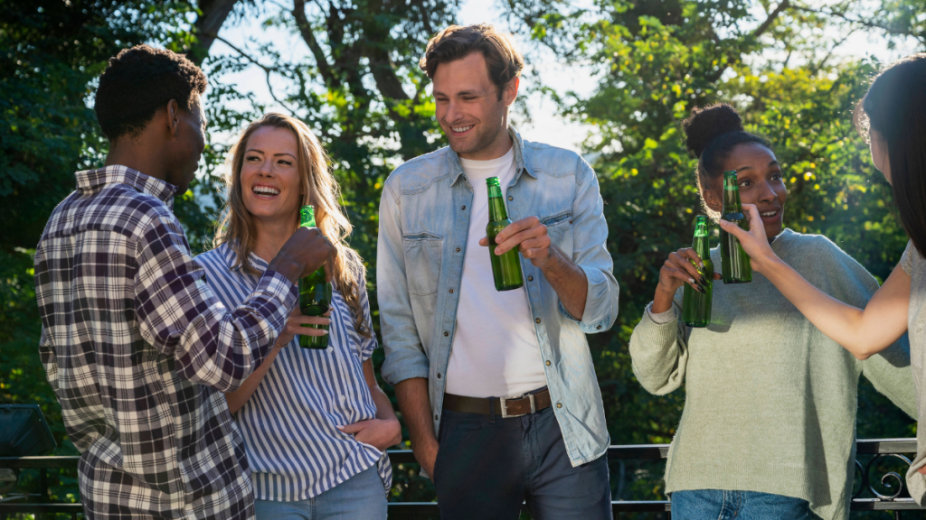 Eine Gruppe von Menschen im Garten mit Bierflaschen in der Hand.