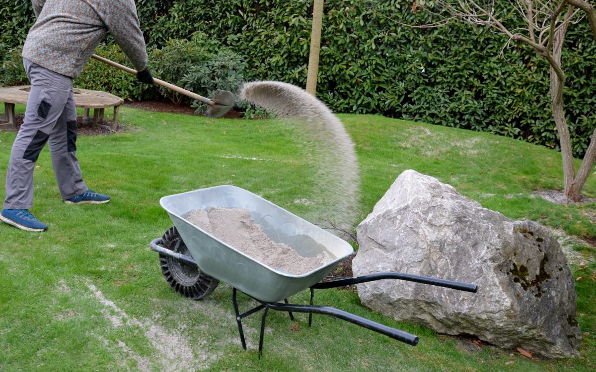 Ein Mann beim Rasen sanden in seinem Garten.