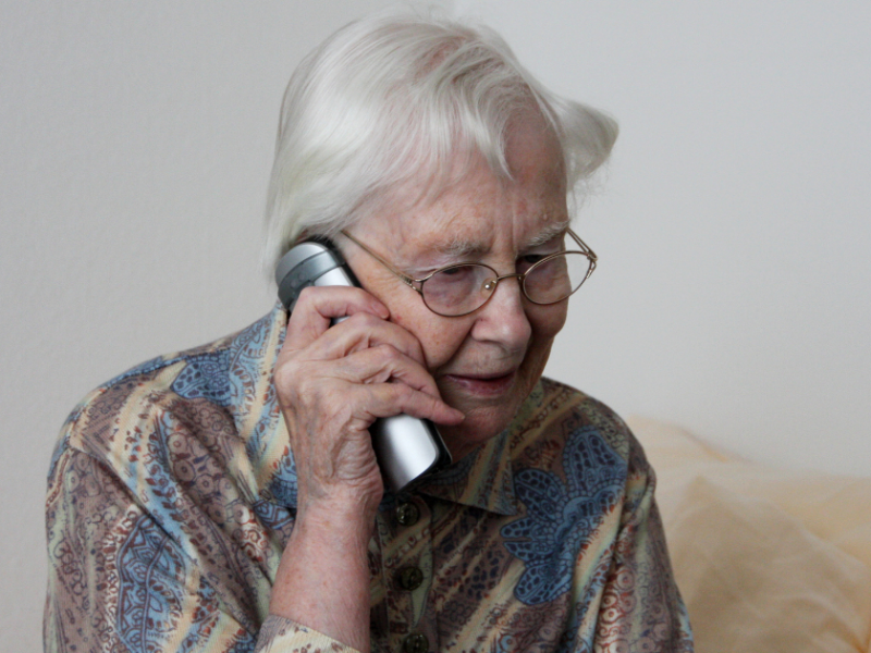 Alte Frau hat ein Telefon ans Ohr.