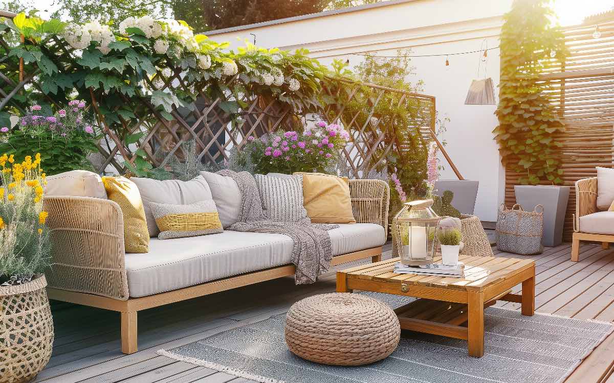 Ein gemÃ¼tlicher Balkon mit Sofa-MÃ¶beln und Sichtschutz-Pflanzen im Hintergrund.