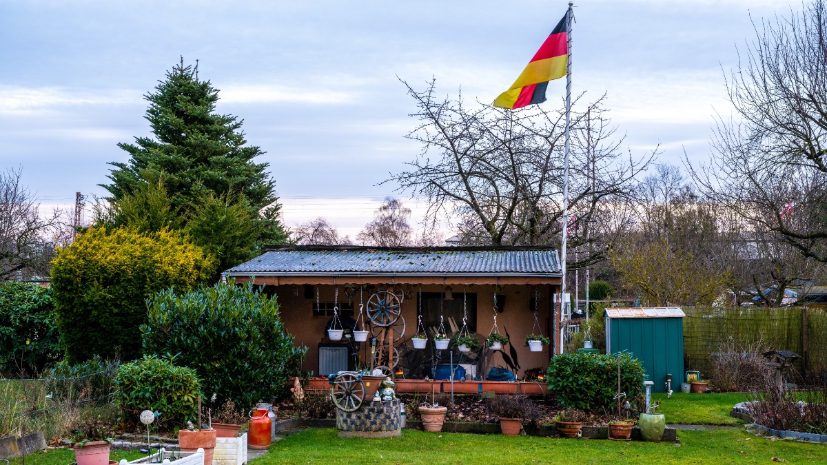 Eine Deutschlandflagge an einem Fahnenmast in einem Schrebergarten