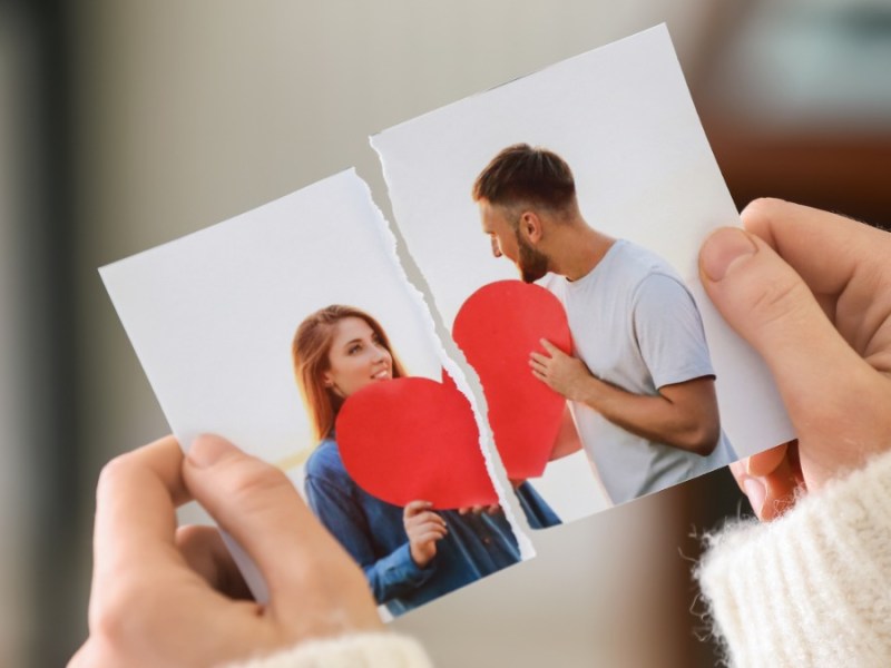 Frau hält ein zerrissenes Foto mit einem Liebespaar in der Hand