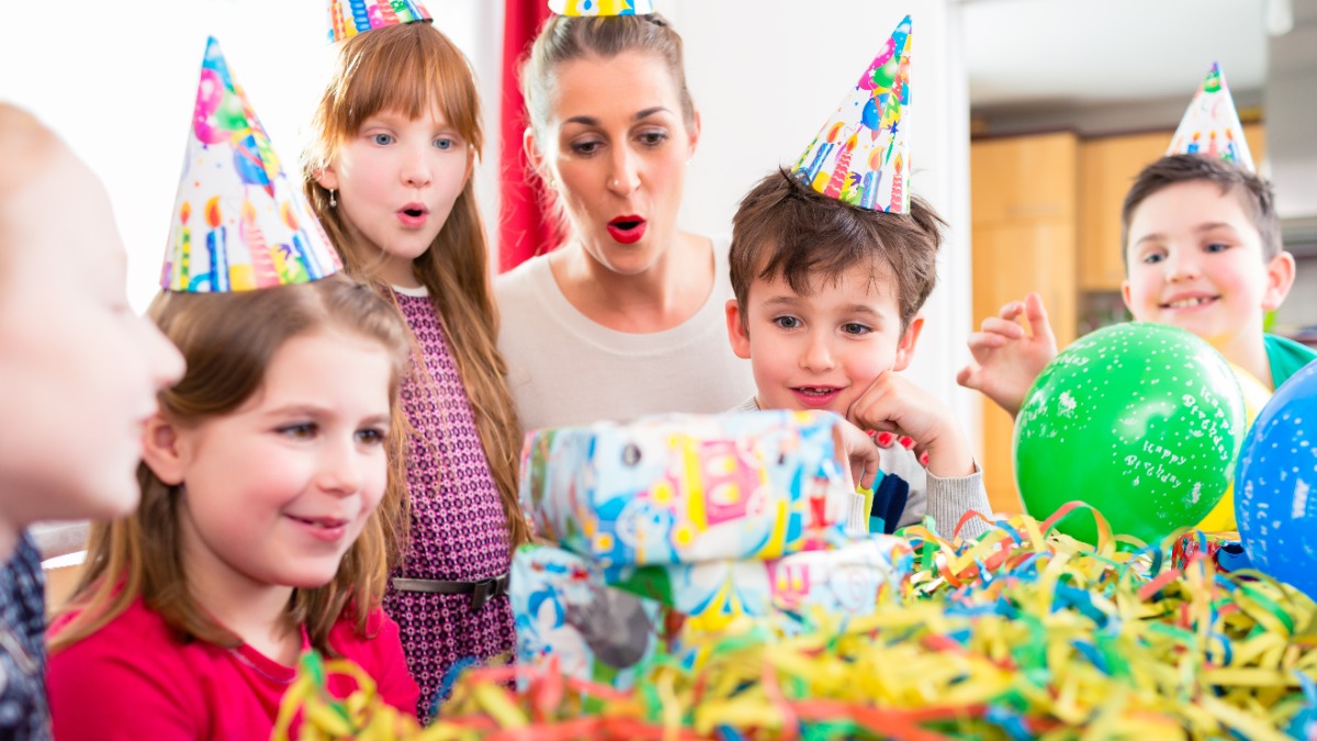 Kleine Kinder mit PartyhÃ¼ten sitzen an einem Geburtstagstisch