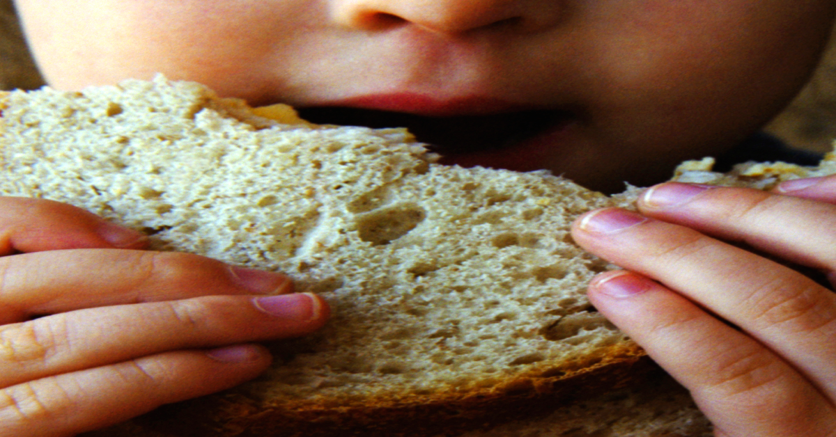 Ein Kind isst eine Scheibe Brot.